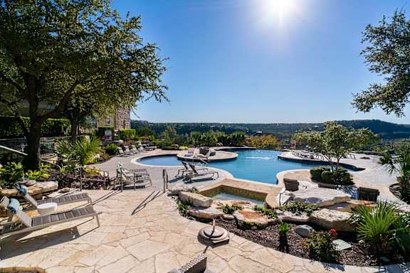 A sunny day at a poolside with a view of the hills.