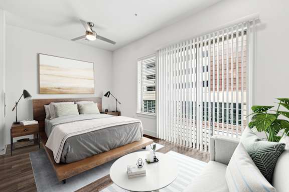 A bedroom with a large bed, a ceiling fan, and a painting on the wall.