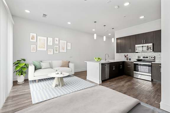 A modern living room with a white sofa and a kitchen area in the background.