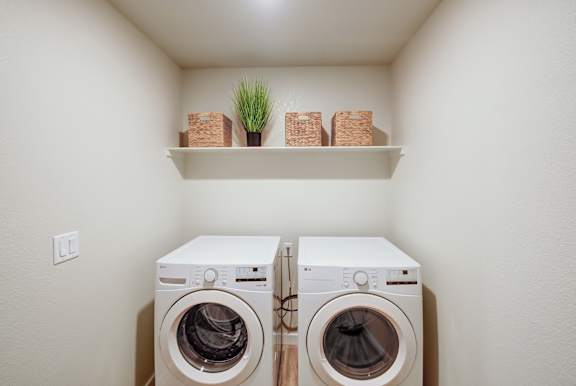 Two white front load washing machines in a small laundry room.