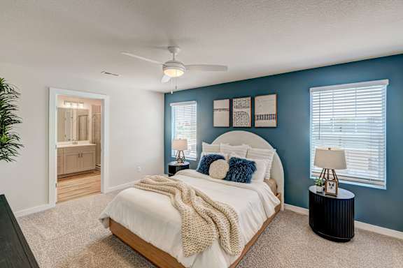 A bedroom with a bed, nightstand, and a plant.