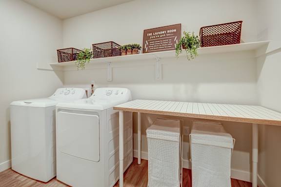A laundry room with a washer and dryer and a bench.