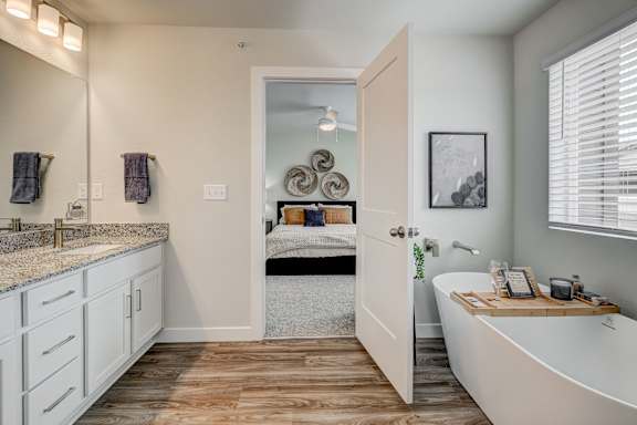 A bathroom with a tub, sink, and mirror.