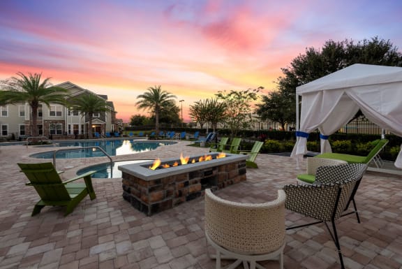 a patio with a fire pit and chairs and a pool