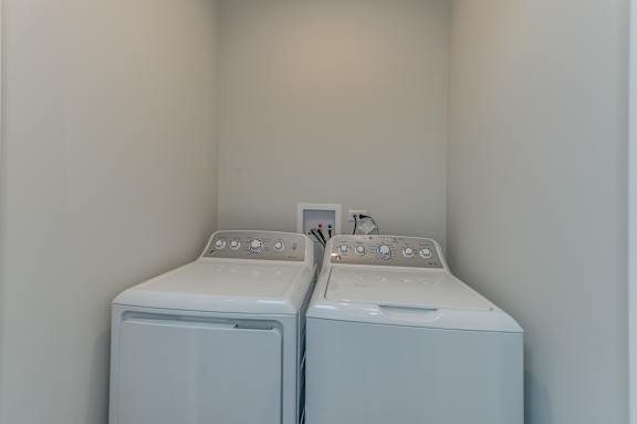 Two white front loading washing machines in a laundry room.