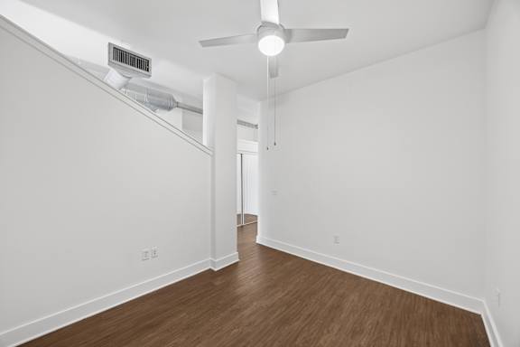 A room with a ceiling fan and wooden flooring.