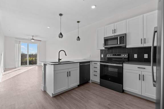 A modern kitchen with white cabinets and black appliances.