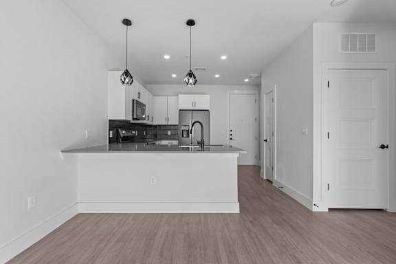 A kitchen with a white island and wooden floors.