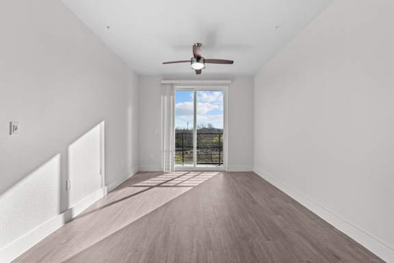 A room with a ceiling fan and a view of the sky through a window.