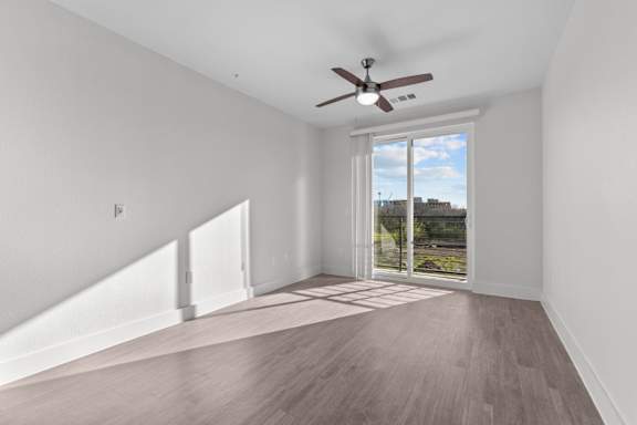 A room with a ceiling fan and sliding glass doors.