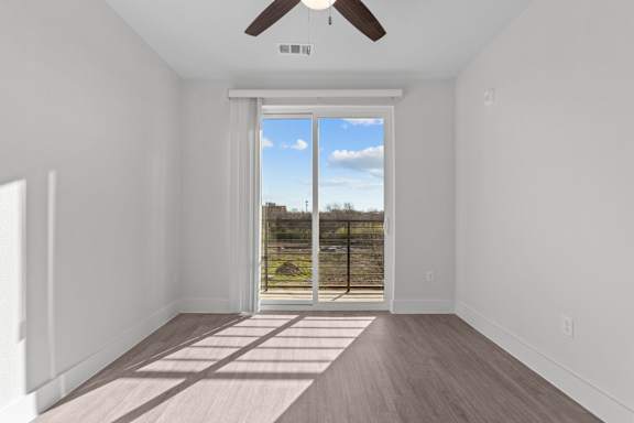 A room with a sliding glass door leading to a balcony.