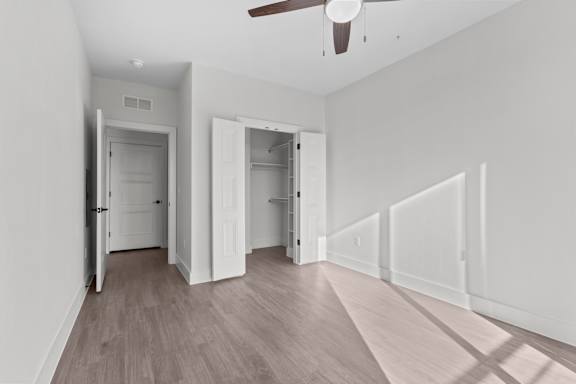 A room with a ceiling fan and wooden flooring.