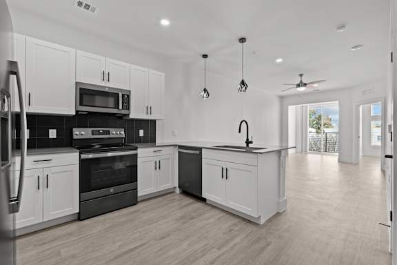 A modern kitchen with white cabinets and black appliances.