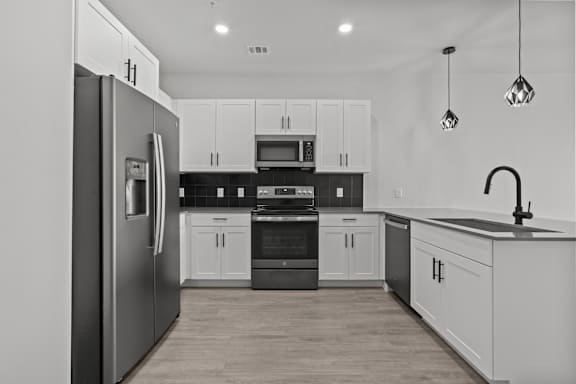 A modern kitchen with a refrigerator on the left and a sink on the right.