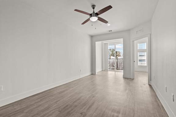 A room with a ceiling fan and wooden flooring.