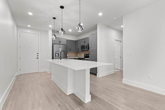 A modern kitchen with a white island and pendant lights.