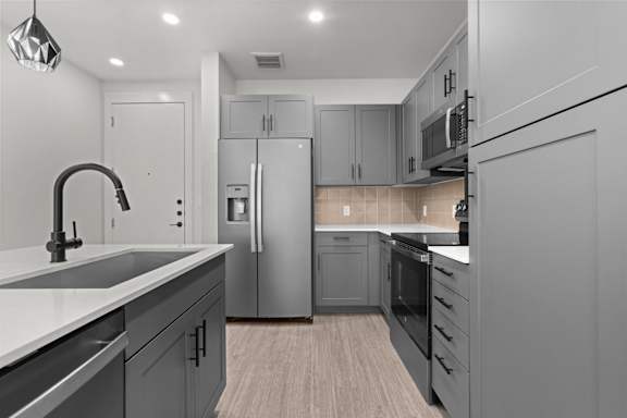 A modern kitchen with a sink, refrigerator, and oven.