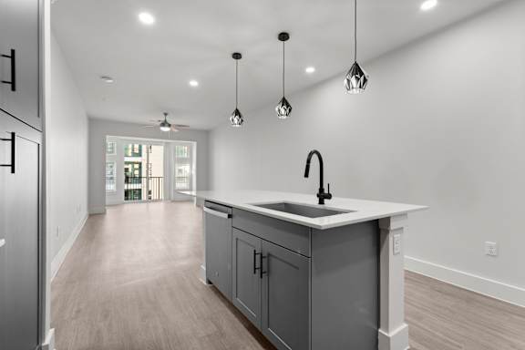 A modern kitchen with a white countertop and grey cabinets.