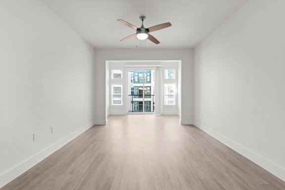 A room with a ceiling fan and a doorway leading to another room.