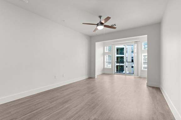 A room with a ceiling fan and a doorway leading to another room.