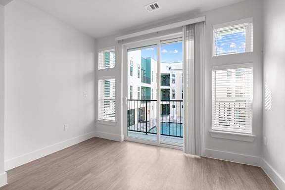 A room with a sliding glass door leading to a balcony.
