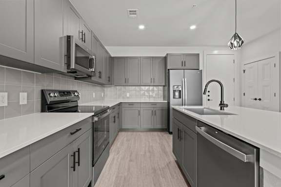 A modern kitchen with a white countertop and grey cabinets.
