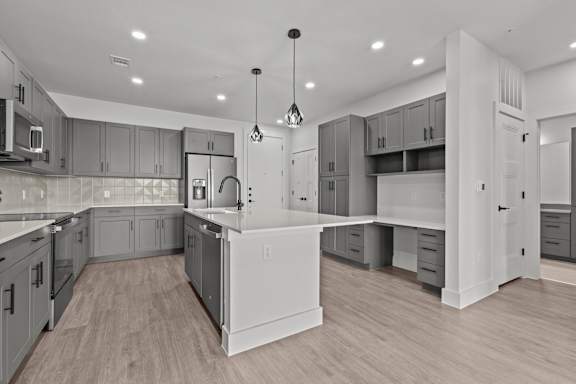 A modern kitchen with wooden floors and grey cabinets.