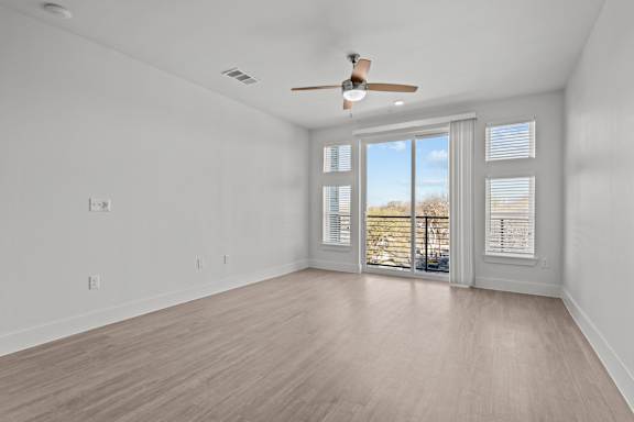 A room with a ceiling fan and sliding glass doors.