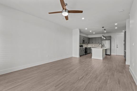 A spacious kitchen and living room with a ceiling fan and light fixture.