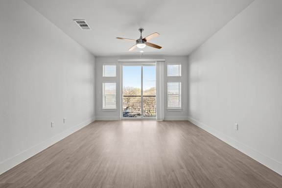 A room with a ceiling fan and a sliding glass door.
