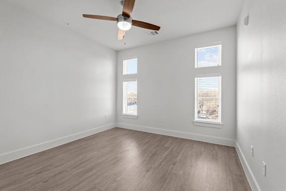 A room with a ceiling fan and two windows.