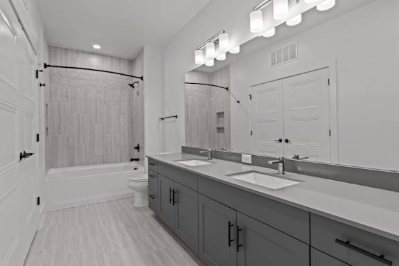 A bathroom with a white tub, sink, and mirror.