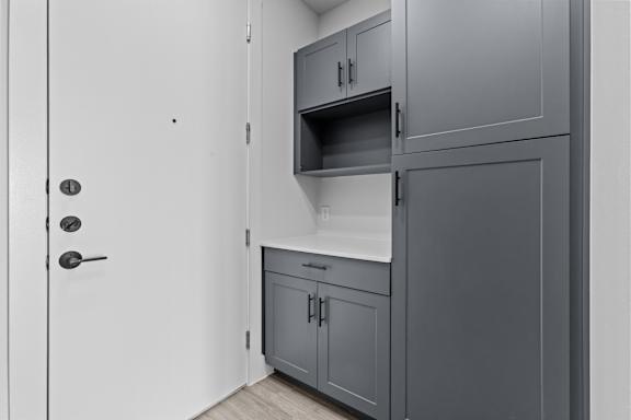 A kitchen with grey cabinets and a white door.