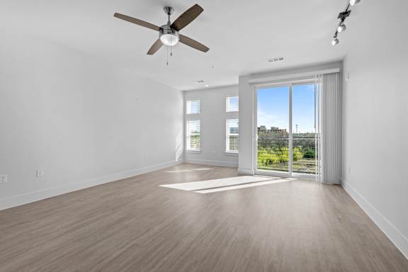 A room with a ceiling fan and sliding glass doors.