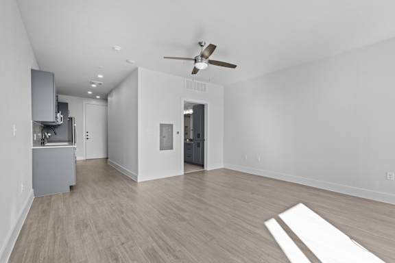 A spacious room with a ceiling fan and lighting fixtures.