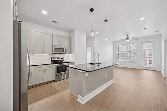 A modern kitchen with a large island and stainless steel appliances.