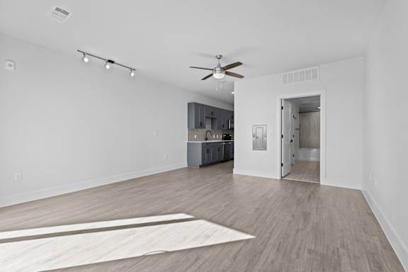 A spacious room with a ceiling fan and a rug on the floor.