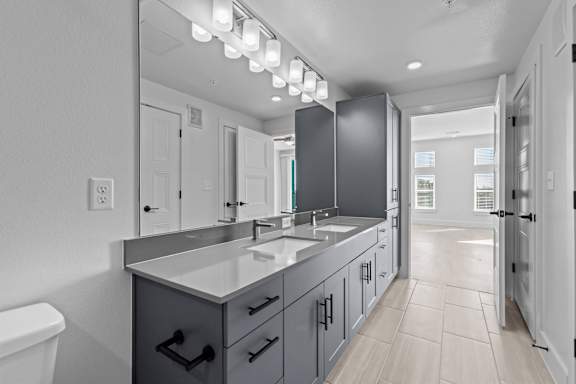 A modern bathroom with a white countertop and a large mirror.