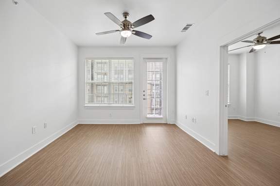 A room with a ceiling fan and a door leading to another room.