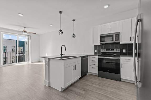 A modern kitchen with white cabinets and black appliances.