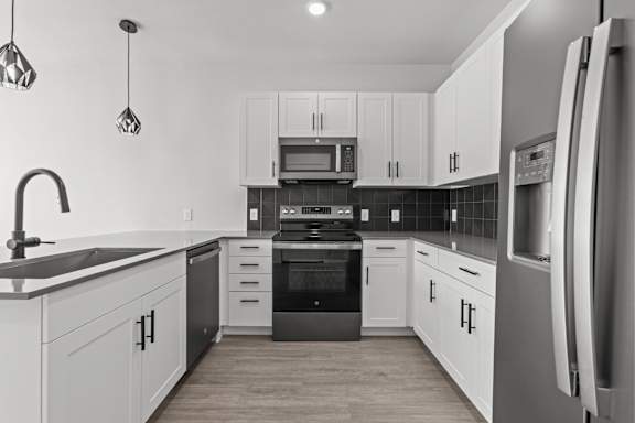 A modern kitchen with white cabinets and stainless steel appliances.