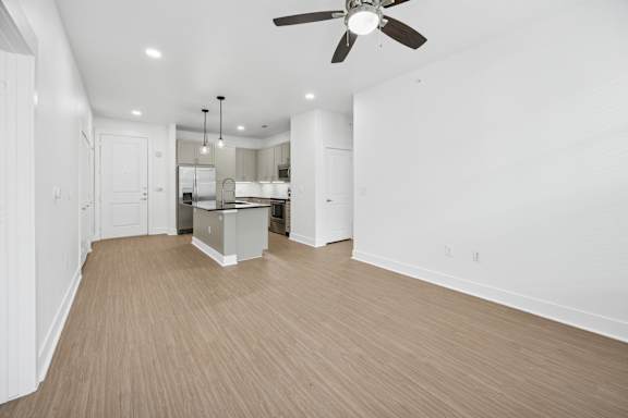A spacious room with a ceiling fan and wooden flooring.