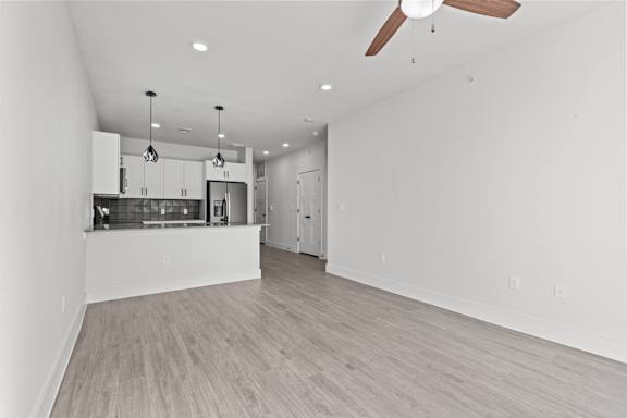 A spacious kitchen with a bar area and a ceiling fan.