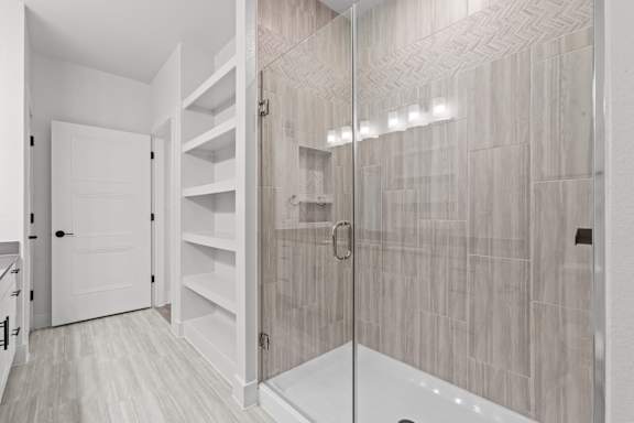 A bathroom with a walk-in shower and a white door.