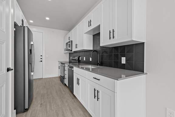A kitchen with white cabinets and a black counter top.