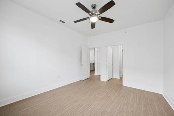 A room with a ceiling fan and light fixture, and a wooden floor.