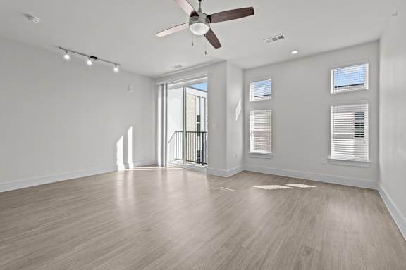 A spacious room with a ceiling fan and lighting fixtures.