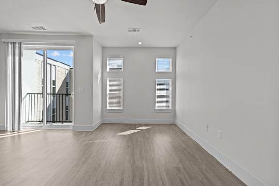 A spacious room with a sliding glass door leading to a balcony.