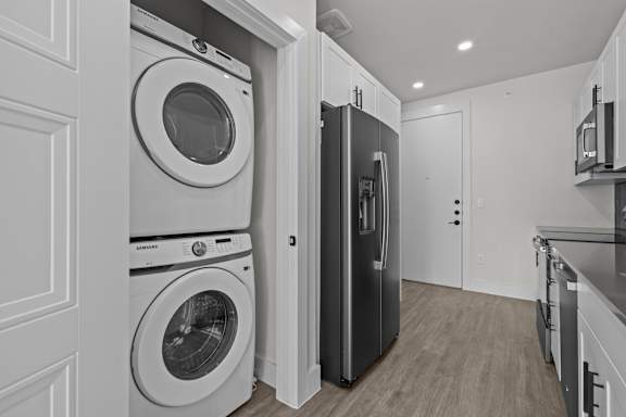 A black refrigerator is in a kitchen with a white washer and dryer.