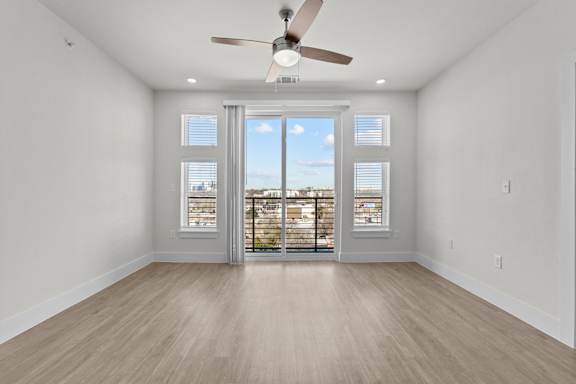 A room with a ceiling fan and sliding glass doors.